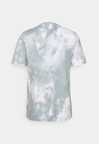 Tyrkysově zelené tričko s krátkým rukávem a kulatým výstřihem, s motivem tie-dye. Má měkkou, texturovanou látku a variabilní vzory připomínající mraky.
