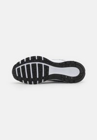 Black and white athletic shoe sole with textured rubber for grip, featuring distinct tread patterns and a circular accent near the heel.