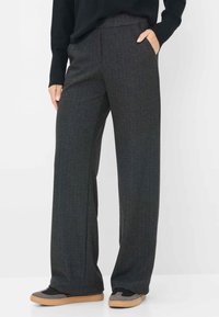 Grijze herringbone wijde broek met een vlakke voorkant en zijzakken, gecombineerd met zwart-grijze sneakers. De stof lijkt textuur te hebben.