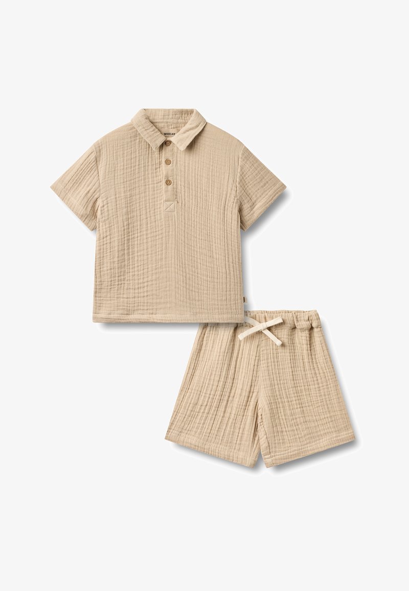 Polo beige à manches courtes avec trois boutons et short assorti à cordon de serrage en tissu texturé léger.