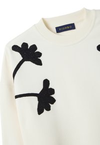 Maglione crema con applicazioni floreali nere testurizzate, scollatura rotonda e polsini a coste. Etichetta con la scritta "PIOMBO."