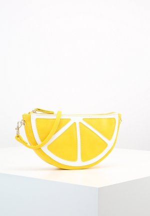 Keltainen nahkalaukku, joka on muotoiltu sitruunalohkoksi, valkoisilla yksityiskohdilla, vetoketjukiinnityksellä ja irrotettavalla olkahihnalla.