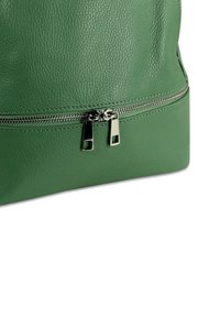 Groene leren tas met gestructureerde afwerking, voorzien van een horizontale ritssluiting en ritsshangers in zilverkleur. Rond bodemvorm met minimale accenten.