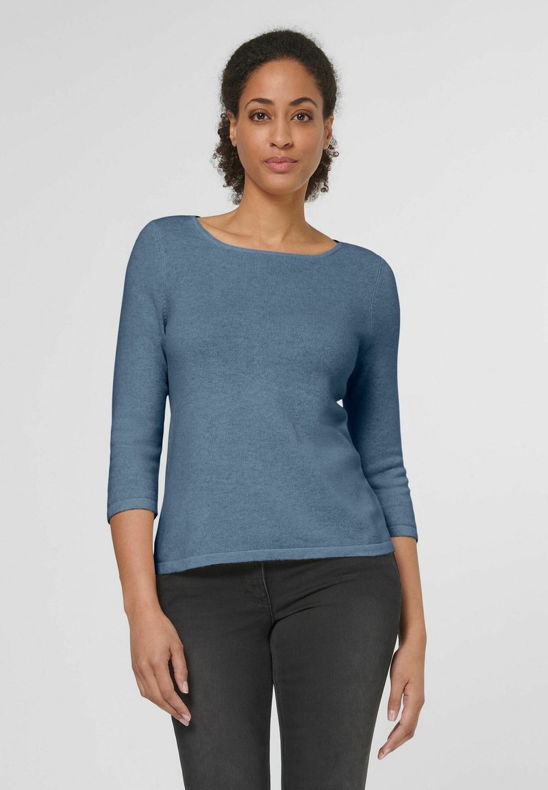 Blauer Strickpullover mit Rundhalsausschnitt und Dreiviertelärmeln. Glatte Textur und taillierte Passform, kombiniert mit dunkelgrauen Jeans.