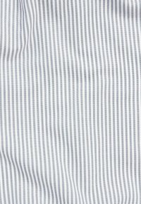 Tissu blanc avec de fines rayures grises, doté d'une texture lisse et d'un motif distinct. Le tissu tombe doucement, mettant en valeur les lignes.