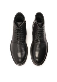 Botas de tobillo de piel negra con un acabado suave, con un cierre de cordones en la parte delantera y una cremallera lateral para facilitar el uso. Diseño de punta redonda.