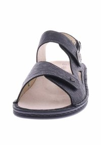 Schwarze Sandale mit offenem Zehenbereich, überkreuzten Riemen und verstellbarem Schnallenverschluss. Verfügt über ein strukturiertes Obermaterial und eine weiche, gepolsterte Innensohle.
