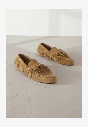 Barna nubuk mokaszin cipők, frufru díszítéssel, fűzős részletekkel és arany fémlyukakkal. Puha tapintás és kerek orr kialakítás.