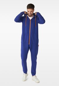 Blue zip-up onesie with an orange zipper and drawstrings, featuring front pockets and ribbed cuffs. Made from soft fabric.