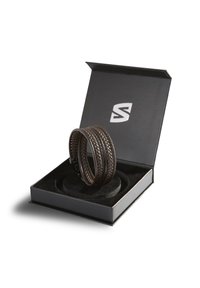 Brauner geflochtener Lederarmband in einer schwarzen Box mit einem Samt-Innenraum, der ein elegantes Design und ein geprägtes Logo auf dem Deckel aufweist.