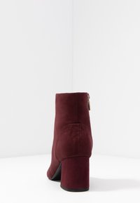 Burgundy mockaskänga med klack, utrustad med en sidozipper och slät yta, designad för en figurnära silhuett.