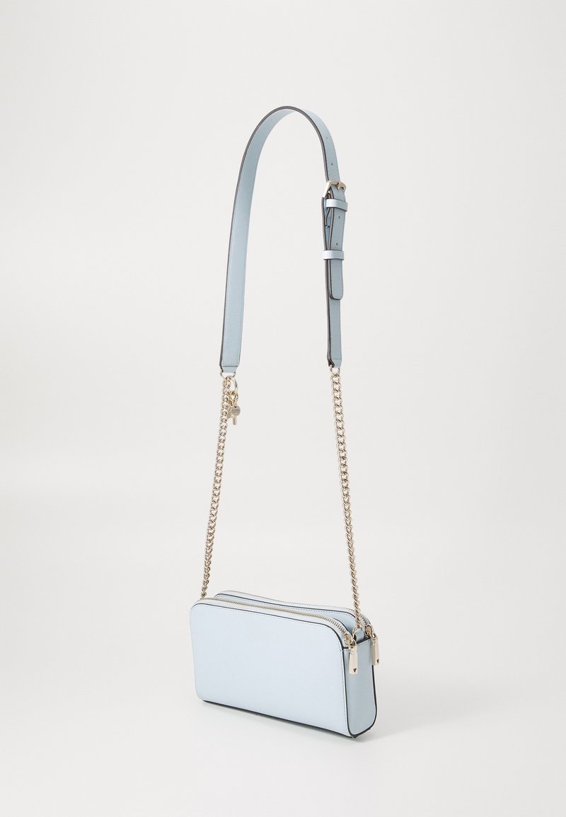 Světlomodrá kabelka přes rameno s hladkou texturou, zipovým uzávěrem a zlatým řetízkovým popruhem. Má štíhlý obdélníkový tvar s černým lemováním.