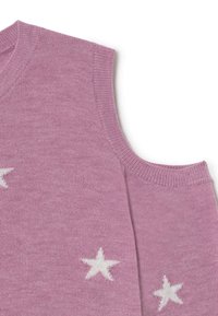 Primer plano de un suéter de punto rosa con patrones de estrellas blancas y un corte al descubierto en el hombro de una manga.