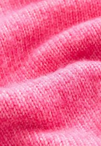 Tessuto lavorato a maglia rosa con una trama morbida. Presenta una combinazione di filati spessi e sottili, creando un motivo sottile con leggere variazioni di tonalità.