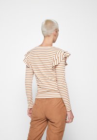 Gestreifte Langarmbluse in Creme und Rost, mit Rüschendetails an den Ärmeln. Aus Baumwolle, figurbetonte Silhouette, schlichtes Design.