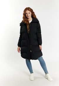 Schwarze Daunenjacke mit hohem Kragen, Frontreißverschluss und geknöpften Akzenten. Verfügt über isolierte Abschnitte und hat eine Knielänge. Trägt man über Jeans und Sneakers.