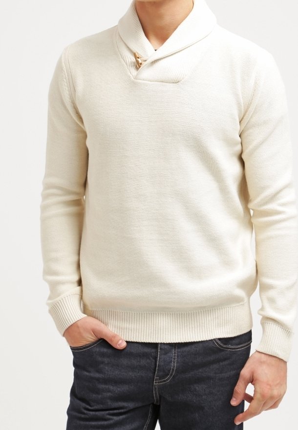 Biały sweter dzianinowy z kołnierzem w stylu szala, z drewnianym zapięciem na guziki. Ściągacze na mankietach i u dołu, noszony z ciemnymi dżinsami. Gładka faktura.