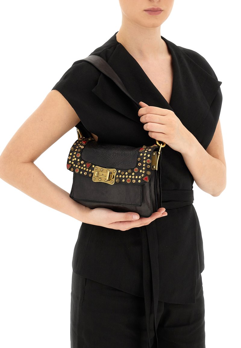 Borsa a tracolla in pelle nera con borchie decorative in rosso e oro. Ha una forma strutturata, un gancio frontale e una tracolla removibile.