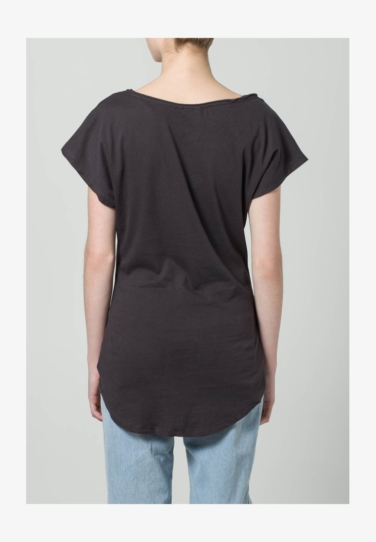 Camiseta de algodón negra con escote ancho, mangas cortas y dobladillo curvado, combinada con jeans de mezclilla azul claro.