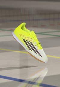 Φωτεινό κίτρινο αθλητικό παπούτσι με κομψό σχέδιο, με μαύρες ρίγες και καουτσούκ σόλα. Υφή στην πάνω πλευρά με  ενισχυμένη μύτη.