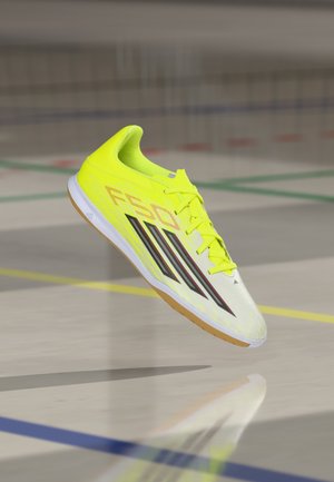 Bright yellow athletic shoe with a sleek design, featuring black stripes and a rubber sole. Textured upper with reinforced toe cap.