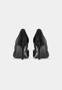 Pantofi cu toc înalt negri, cu un exterior din piele texturată, vârfuri ascuțite și tocuri stiletto. Prezintă decupaje laterale și o căptușeală interioară netedă.