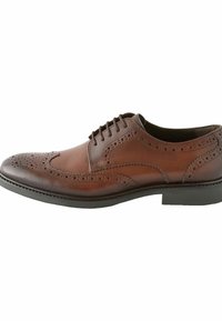 Chaussure habillée en cuir marron avec un design à bout fleuri, des perforations décoratives, un bout rond et une semelle en caoutchouc noire. Équipée de lacets et d'une finition lisse.