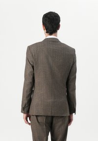 Grå mönstrad kostymjacka med en åtsittande design, som har en notch-lapel och två bakventiler, tillverkad i texturerat tyg med bruna detaljer.