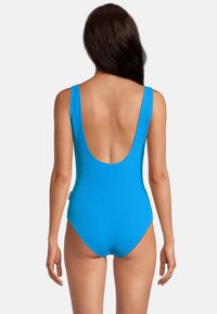 Maillot de bain une pièce bleu avec un design texturé en côtes, des larges bretelles et un dos plongeant. Présente un tissu doux et une silhouette ajustée.
