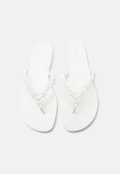 Ζευγάρι λευκών, επίπεδων σανδαλιών με λουριά τύπου αλυσίδα σε απλό ανοιχτό φόντο.