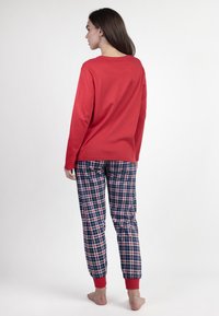 Parte superior roja de manga larga combinada con pantalones de pijama de cuadros azul marino con puños rojos. Fabricados en suave algodón, con un ajuste relajado y un patrón a cuadros.