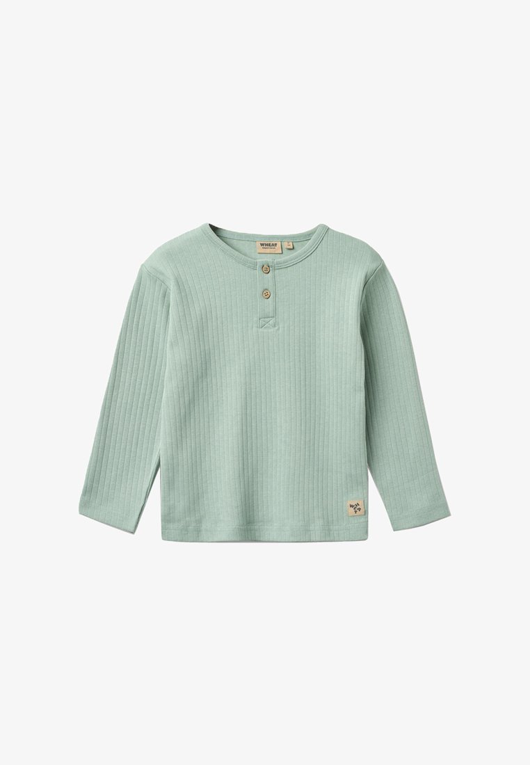 Hellgrünes, geripptes Langarmshirt mit zwei Holzknöpfen und einem kleinen Markenschild nahe dem Saum.