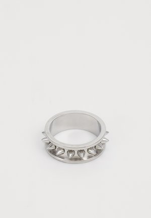 Sølv metallring med jevnt fordelte koniske pigger rundt ringen, vist mot en enkel hvit bakgrunn.