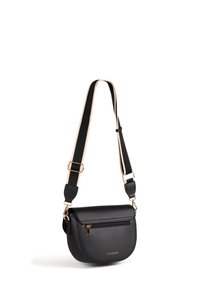 Sac bandoulière en cuir noir avec poche avant zippée dorée et sangle noire réglable avec bords beiges suspendu sur fond blanc.