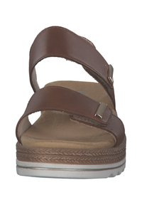 Brown sandals with two adjustable straps, suede insole, and a contrasting sole. Features metal accents and a woven texture on the base.