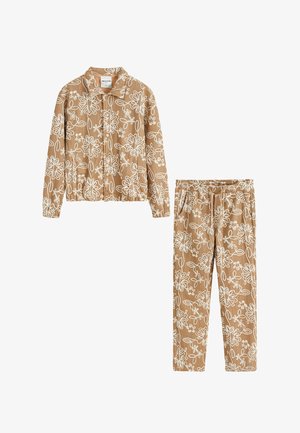 Ensemble veste et pantalon en velours côtelé beige avec des motifs floraux abstraits blancs en lignes, manches longues, et taille élastique au pantalon.