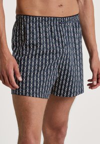 Nachtblau boxer shorts met een herhalend wit patroon. Elastische tailleband met knoopsluiting. Gemaakt van ademend katoen.