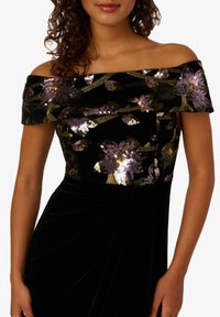 Schwarzes Samtkleid mit schulterfreiem Design und floralem Paillettenverzierungen in Lila und Gold, mit drapiertem Design und plissiertem Rock.