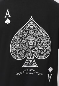 Μαύρο ύφασμα με μεγάλο περίτεχνο λευκό σπαθί που απεικονίζει το πρόσωπο ενός λιονταριού, σύμβολα Άσου και το κείμενο "Τύχη και Δύναμη Από το 1958"