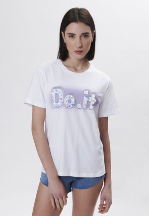 T-shirt en coton blanc arborant la phrase "Fais-le" en lettres iridescentes avec des accents décoratifs. Manches courtes et coupe décontractée.