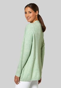 Lichtgroene geribde trui met lange mouwen, ontspannen fit en zijsplitten. Gemaakt van zachte, gestructureerde stof, geschikt voor casual kleding.