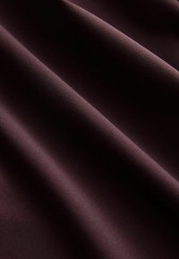 Mørk bordeauxfarvet stof folder sig blødt og glat i bløde folder, der viser en rig tekstur med en let glans og uden synlige mønstre eller accenter.