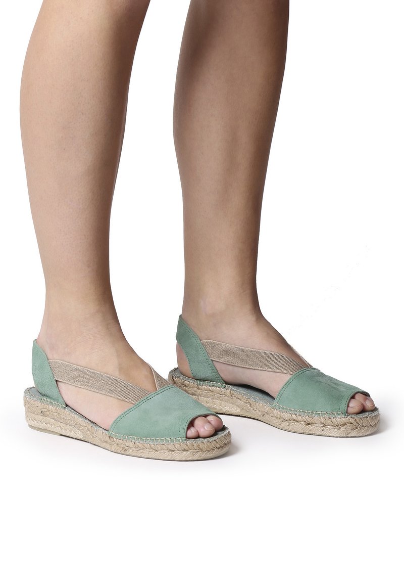 Vihreät mokka espadrillesandalsit, joissa on avonainen varvas, elastiset hihnat ja juutti-pohja. Suunnittelussa on tasapohja mukavuutta varten.