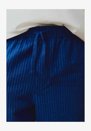 Temno modre črtaste hlače z vrvico v pasu. Tkanina ima gladko teksturo, z drobnimi vertikalnimi črtami svetlejše odtenka.