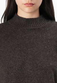 Tmavě šedý vlněný svetr s řaseným vysokým límcem a měkkou texturou, který se vyznačuje jednoduchým a klasickým designem. Bez viditelných vzorů nebo ozdob.