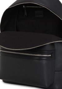 Black leather backpack with a zippered front pocket, textured finish, and a spacious, unlined interior. Zippered closure at the top.