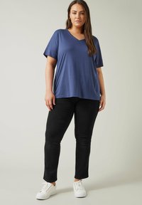 Mörkblå V-ringad t-shirt med korta ärmar, matchad med svarta slim-fit jeans och vita sneakers. Mjuk tyg, avslappnad passform, minimalistisk design.