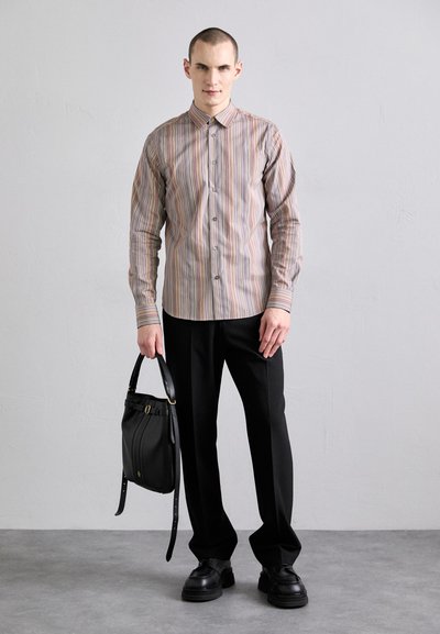 Striped long-sleeve shirt in beige with multicolored stripes, paired with black trousers and a black leather bag with a short handle.