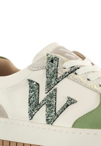 Sneaker blanche avec des accents verts et beiges, présentant un logo "W" texturé et pailleté. Cuir lisse et semelle en caoutchouc avec couture ton sur ton.