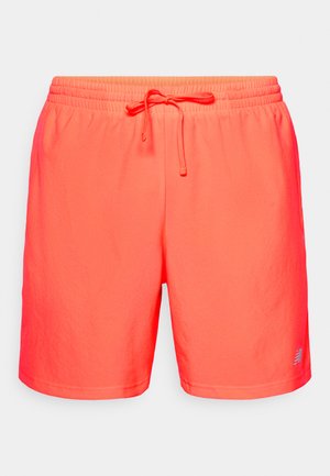 Shorts de sport en corail vif avec taille élastique et cordon de serrage, portant un petit logo gris près de l'ourlet gauche sur fond blanc.